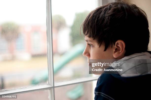 pensive child looking through a window - weeshuis stockfoto's en -beelden