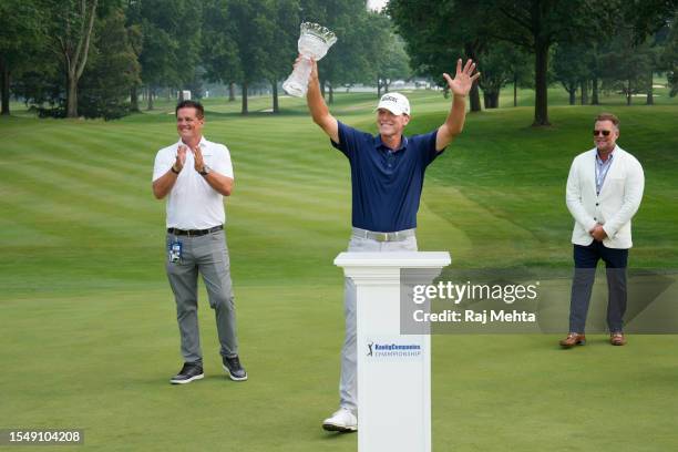 Steve Stricker of the United States raises the trophy in celebration between Matt Kaulig Executive Chairman of the Kaulig Companies Limited and Tim...