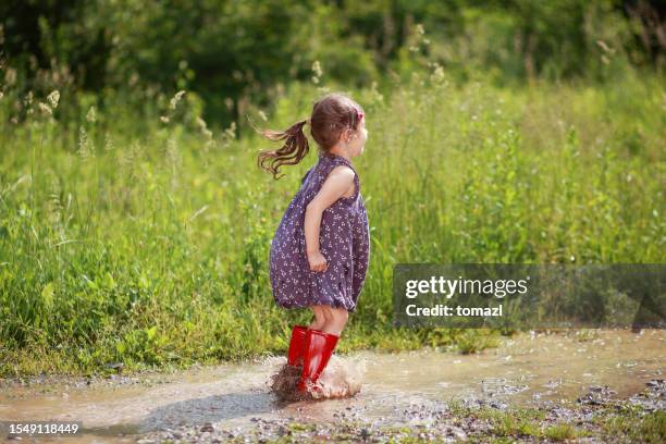 child enjoying a big puddle of mudd - kid stomping feet stock pictures, royalty-free photos & images