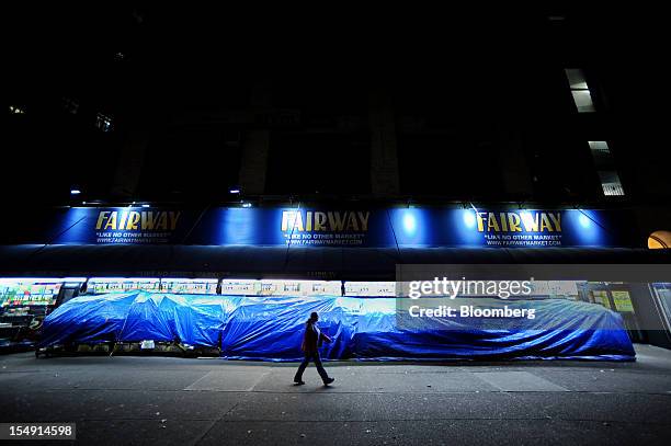 Pedestrian walks past fruit and vegetable stalls covered with tarps on Broadway in New York, U.S., on Sunday, Oct. 28, 2012. The U.S. Securities...