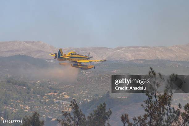 Plane flies over a woodland as teams try to extinguish wildfires in Asklipio village on Rhodes island, Greece on July 23, 2023. Some 19,000 people...