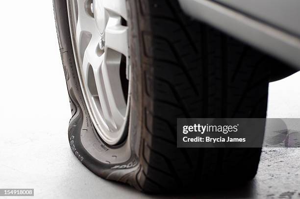 a flat tire is the focus isolated on white - flat tyre stock pictures, royalty-free photos & images