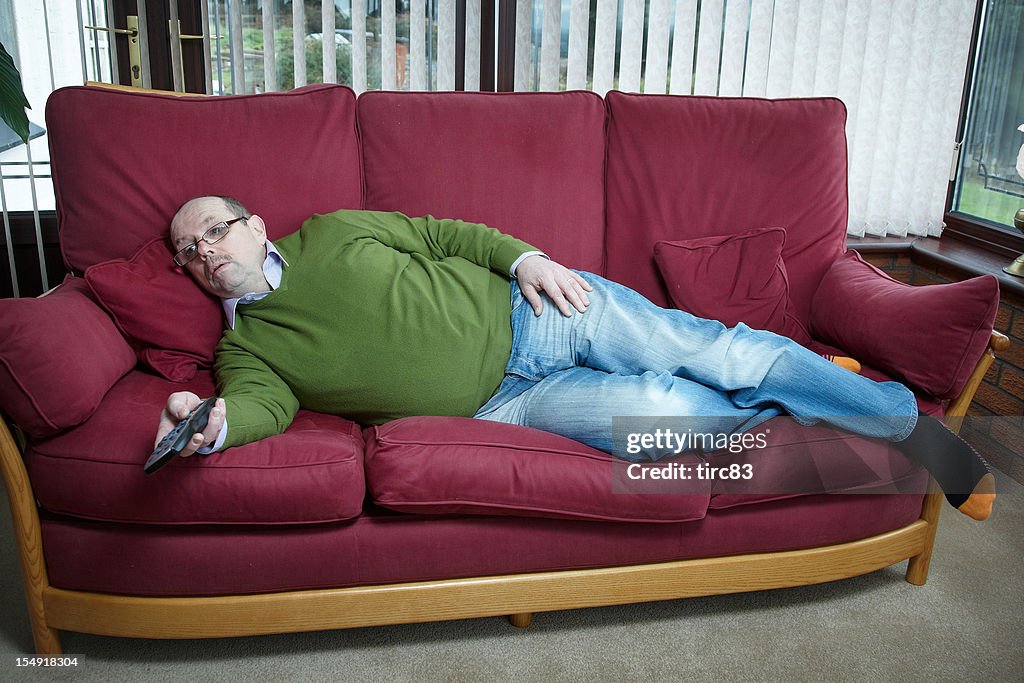 Retrato de homem maduro Deitada no sofá com controlo remoto de TV