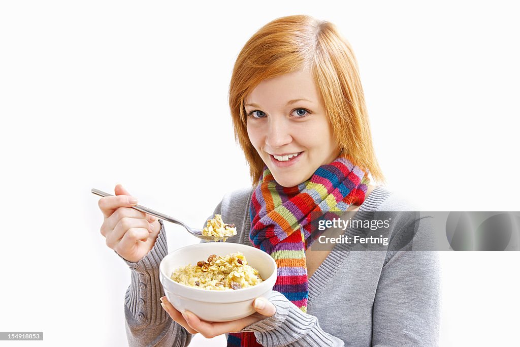 Happy young woman eating a bowl of oatmeal