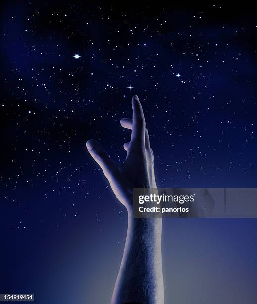 dark blue and black graphic of a hand reaching for stars - reiken stockfoto's en -beelden
