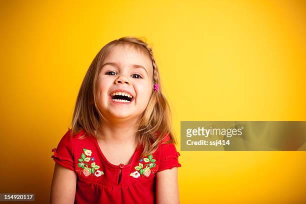 süßes kleines mädchen lachen während auf gelbem hintergrund - blonde girl smiling stock-fotos und bilder