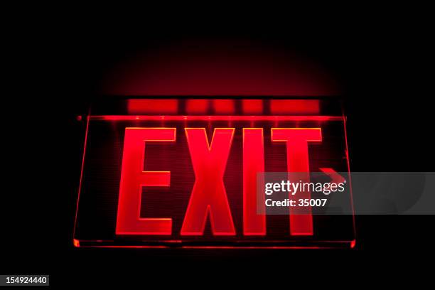a red illuminated exit sign on black - exit sign stock pictures, royalty-free photos & images