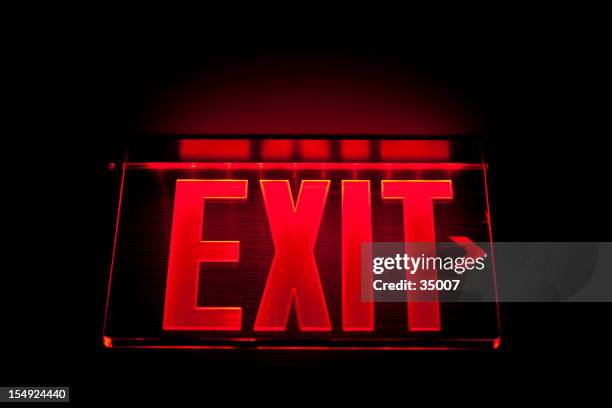 a red illuminated exit sign on black - exit sign stock pictures, royalty-free photos & images