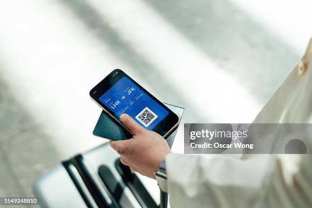 young woman holding smartphone with electronic flight tickets - self service check in stock pictures, royalty-free photos & images