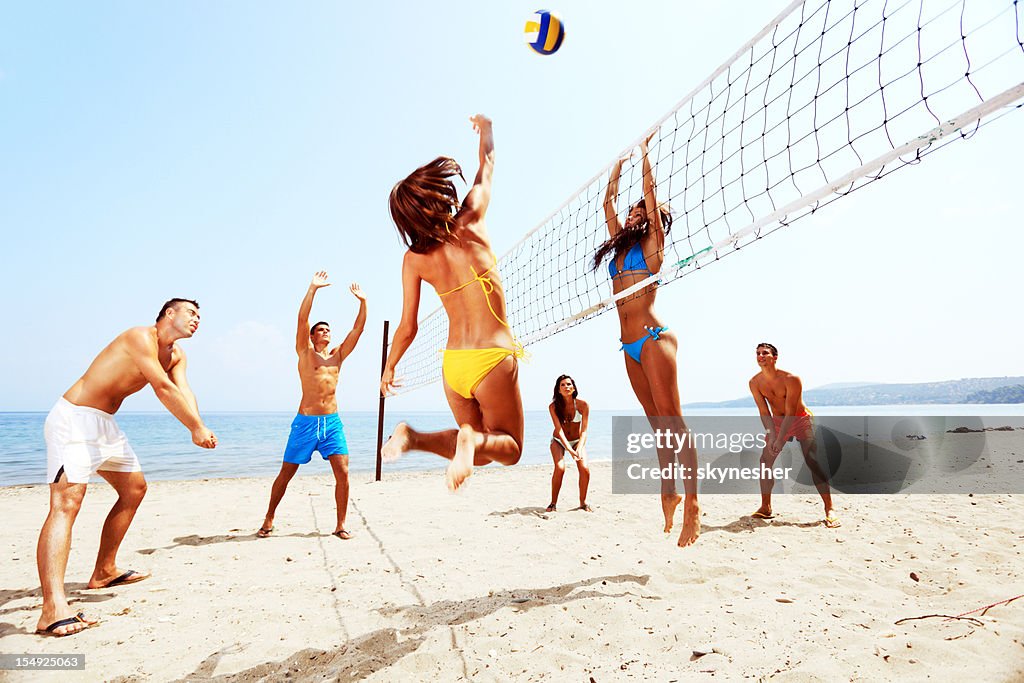 Large team of a people  are playing beach volleyball