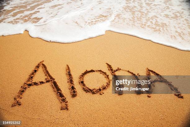 inviting "aloha" written in the sand with surf. - aloha stock pictures, royalty-free photos & images