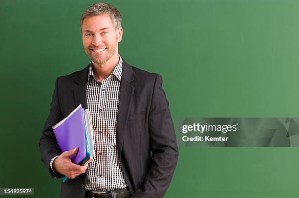 teacher carrying books and standing by the blackboard - teacher with folder stock pictures, royalty-free photos & images
