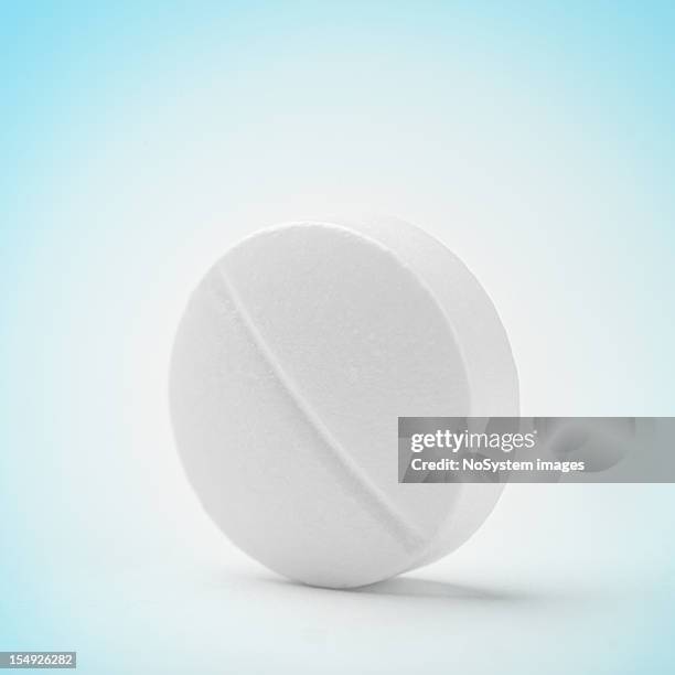 a minuscule macro dissolving tablet on a blue background - exercise pill stockfoto's en -beelden