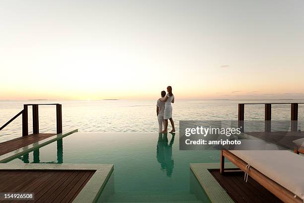 coppia godendo il tramonto a bordo piscina - viaggio di nozze foto e immagini stock