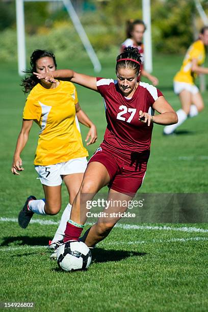 female soccer player in dark red breaks away from defender - offense sporting position stock pictures, royalty-free photos & images