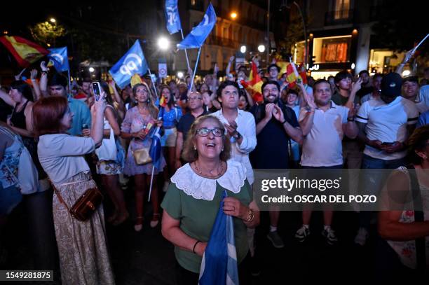 Supporters hold Spain's national flag as they wait for elections results in front of the headquarters of the leader and candidate of conservative...