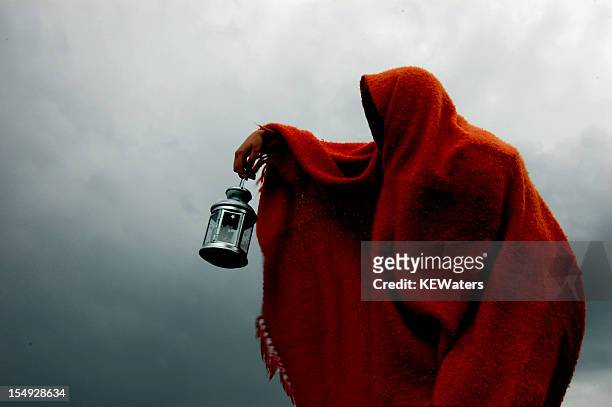 hooded crone holds lantern in storm - a morte imagens e fotografias de stock