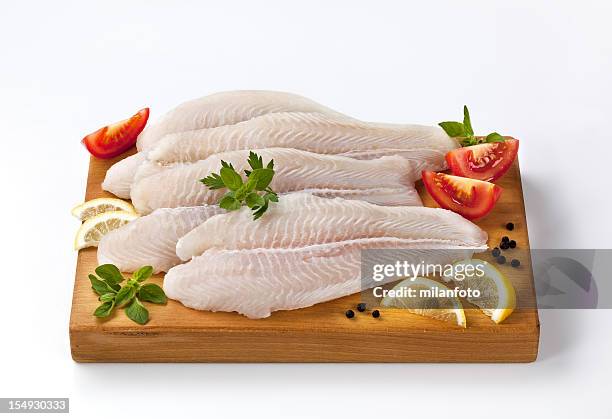 frozen fish fillets on a cutting board - frozen fish fillets stockfoto's en -beelden