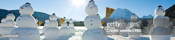 snowmen regiment - snowman with hat and broom in sun - funny snow globe stock pictures, royalty-free photos & images