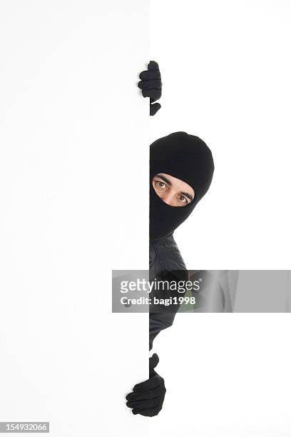 black-wearing thief spying out the white wall/background - thief stock pictures, royalty-free photos & images