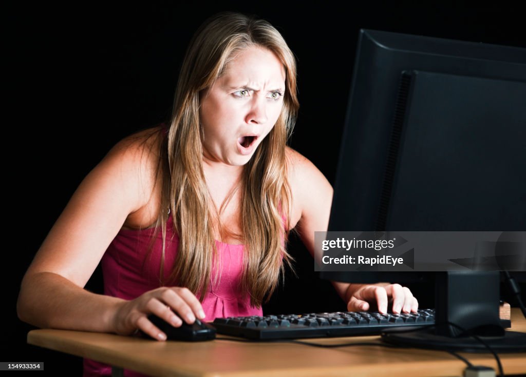 Pretty blonde is shocked by what's on computer monitor