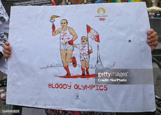 Protester in Krakow holds a powerful poster with Putin and Lukashenko's images, featuring an Olympic torch covered in blood and the words 'Bloody...