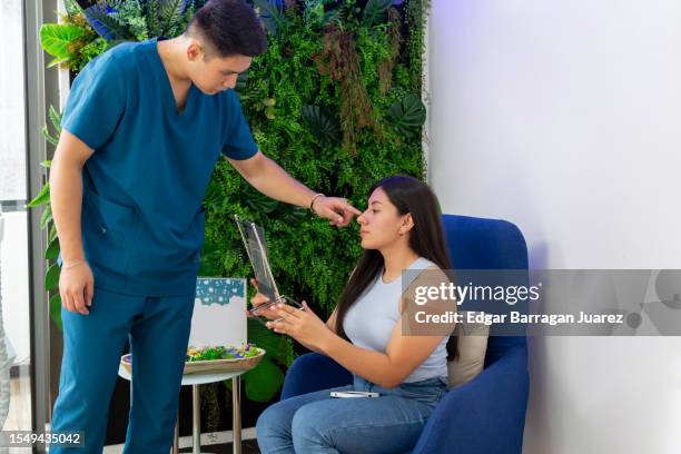 dermatologist explains to his patient the imperfections on her face that they are going to treat in the consultation while he receives her in the lobby - dermatologists talking to each other patient stock pictures, royalty-free photos & images