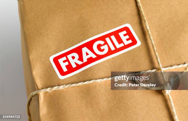 brown paper parcel with fragile sticker - handle with care stockfoto's en -beelden