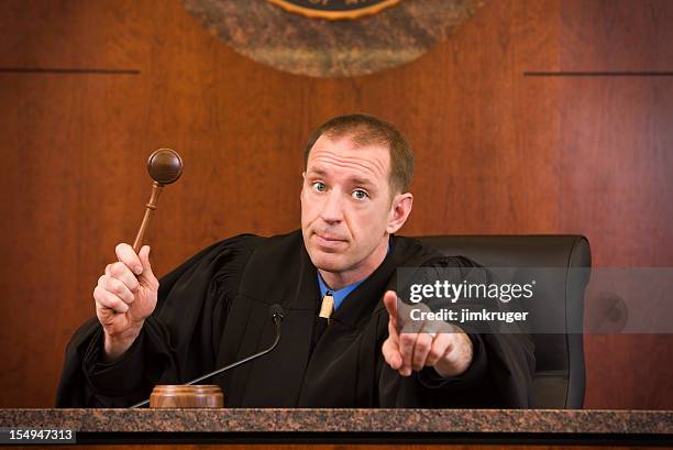 upset judge swinging gavel and pointing - judge stockfoto's en -beelden