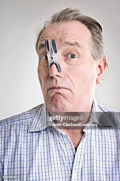 businessman with peg on his nose. - pinching nose stockfoto's en -beelden