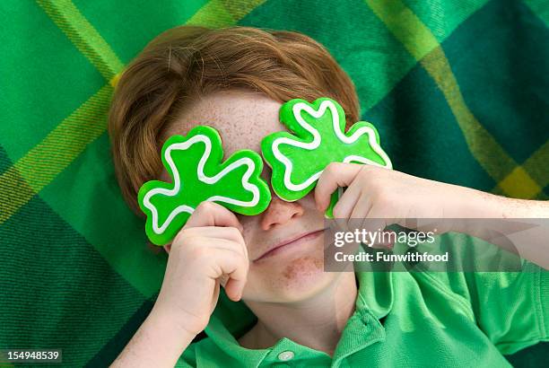 boy leprechaun, smiling irish child & st. patrick's day shamrock cookies - leprechaun stock pictures, royalty-free photos & images