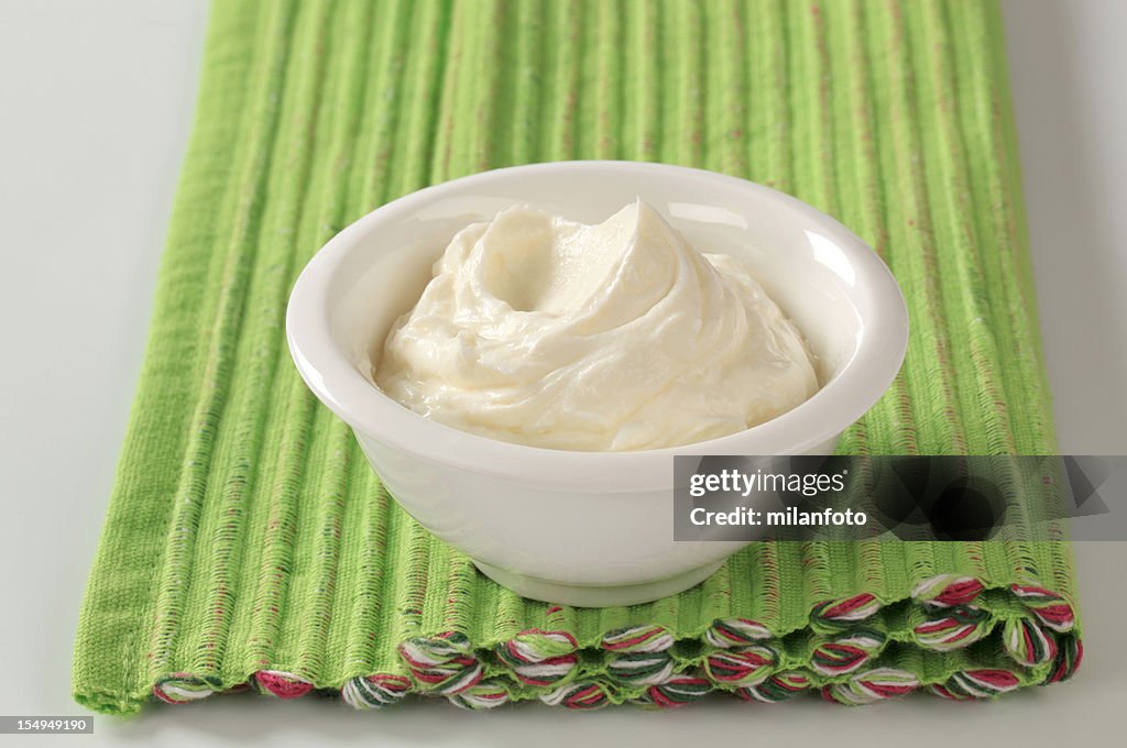 White bowl of cream cheese on green placemat