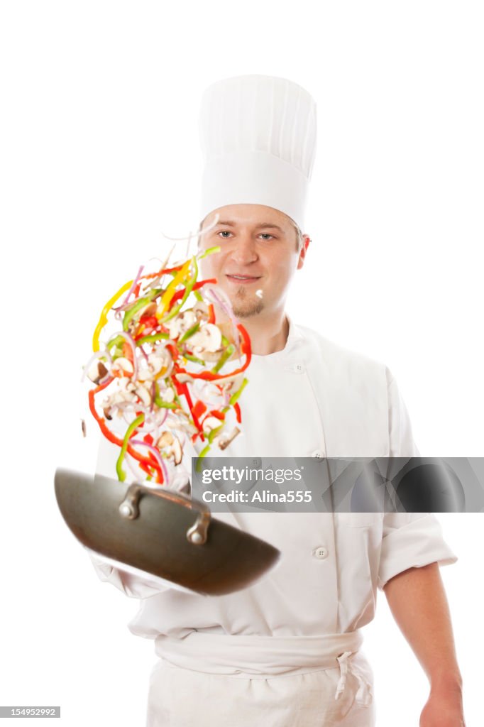 Portrait of happy chefs tossing vegetables in a wok