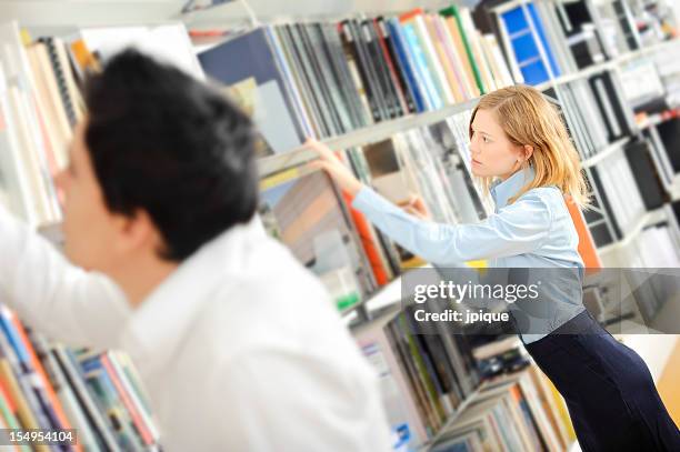 teenagers searching a book in the library - differential focus education reach stockfoto's en -beelden