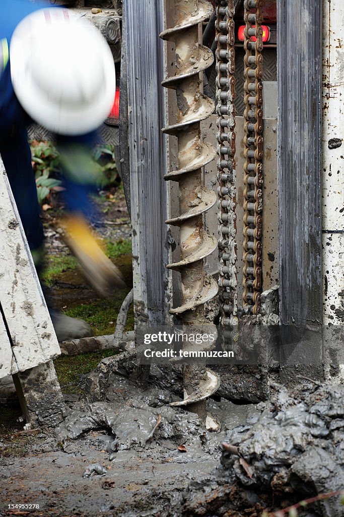 A man with hard hat operating a large industrial drill.