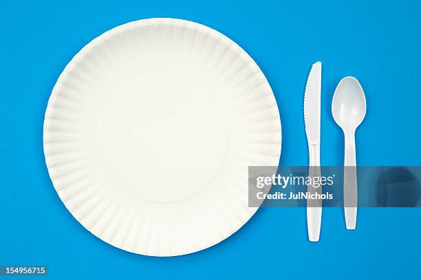 a paper plate next to plastic utensils on a blue table - paper plate stock pictures, royalty-free photos & images