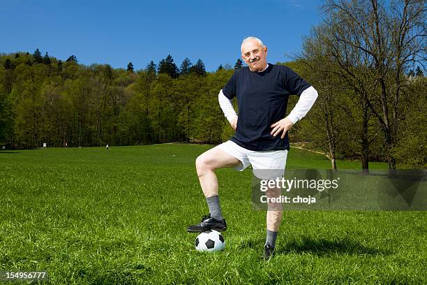 senior soccer player in  park with his foot on ball - senior kicking stock pictures, royalty-free photos & images