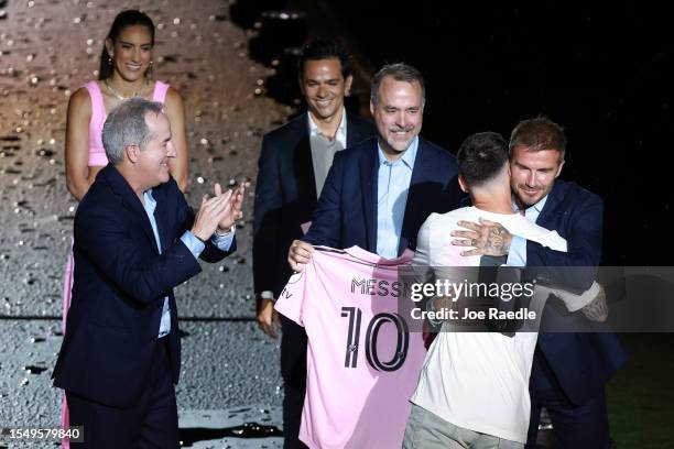 Managing owner Jorge Mas, Marc Anthony and co-owner Jose Mas react as Lionel Messi hugs co-owner David Beckham during "The Unveil" introducing Lionel...