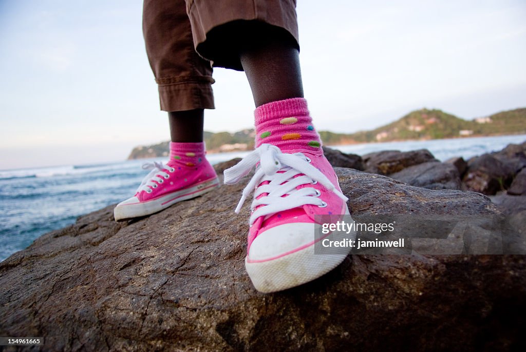 Pink casual shoes chilling on rocks near beach