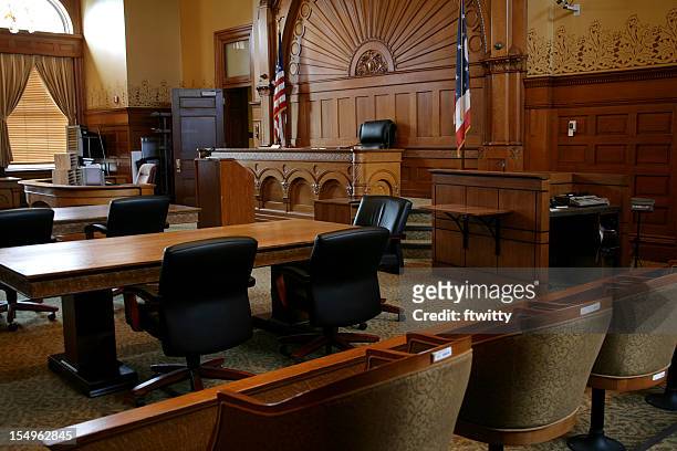 an empty, brown-paneled courtroom with flags - law court stock pictures, royalty-free photos & images