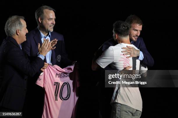 Lionel Messi hugs co-owner David Beckham as managing owner Jorge Mas and co-owner Jose Mas look on during "The Unveil" introducing Lionel Messi...