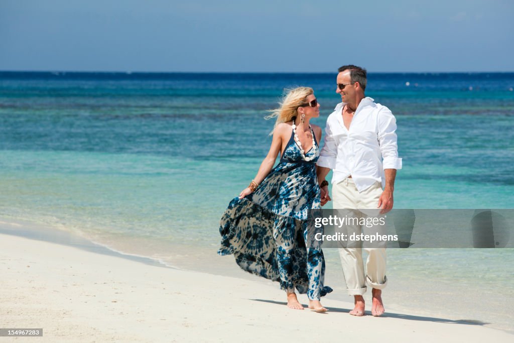 Casal de idade caminhar ao longo da praia Tropical