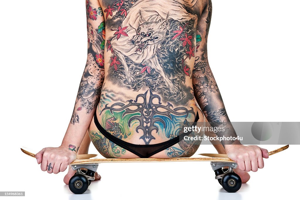 Tattooed woman sitting on skateboard