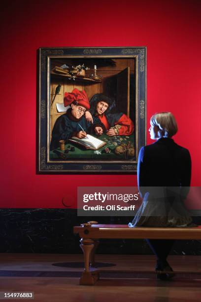 Woman admires a painting by a Follower of Marinus van Reymerswaele entitled 'The Misers' in the exhibition 'The Northern Renaissance: Durer to...