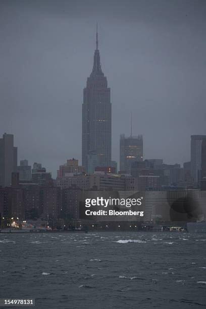 The Empire State Building is seen past waves in the East River in New York, U.S., on Monday, Oct. 29, 2012. Hurricane Sandy strengthened on its path...