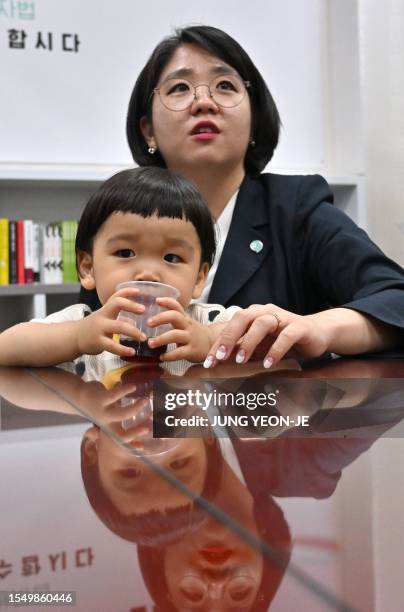 This picture taken on June 2, 2023 shows lawmaker Yong Hye-in speaking while her two-year-old son Bak Dan drinks juice during an interview with AFP...