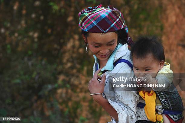 This picture taken on October 23, 2012 shows a young ethnic Hmong hill tribe woman carrying a baby on her back as she makes way home in the...