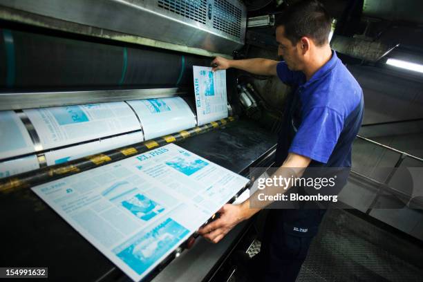 An employee changes El Pais printing press plates on a machine at the El Pais printing plant in Madrid, Spain, on Tuesday, Oct. 30, 2012. Prisa, the...