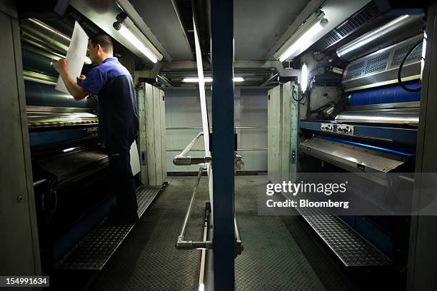 An employee changes El Pais printing press plates on a machine at the El Pais printing plant in Madrid, Spain, on Tuesday, Oct. 30, 2012. Prisa, the...