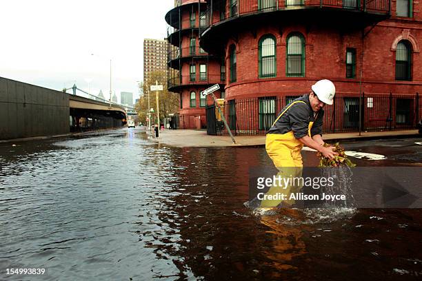 Man clears leaves from a sewer drain in lower Manhattan, October 30, 2012 in New York. The storm has claimed at least 33 lives in the United States,...